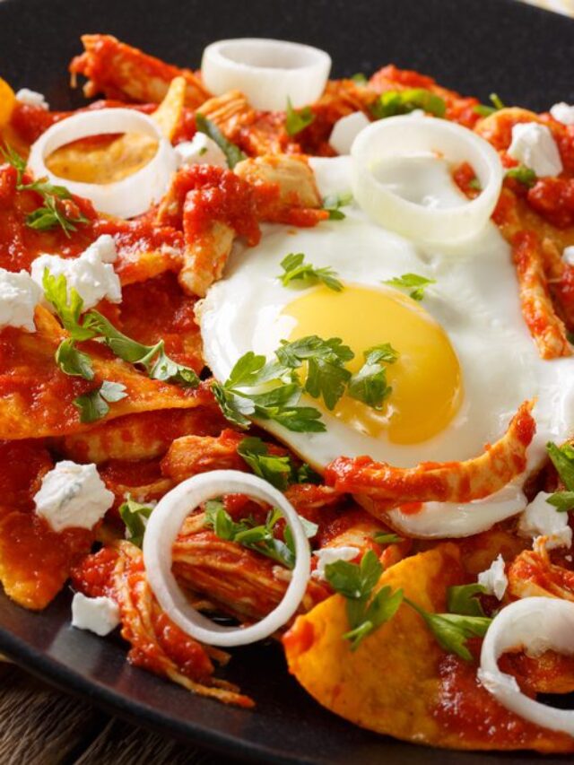 Mexican chilaquiles with fried egg and chicken close-up on a plate.